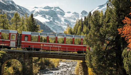 trenino-rosso-bernina-express-panoramico-che-attraversa-un-ponte-con-sotto-un-fiume-e-si-possono-ammirare-nel-sottofondo-le-maestose-montagne-innevate