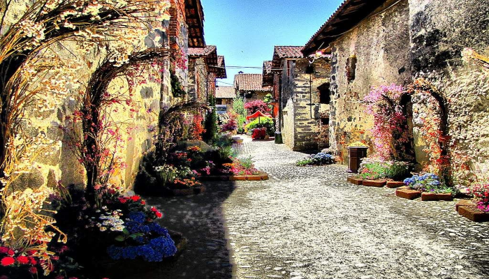 viottolo-caratteristico-nel-ricetto-di-candelo-con-vari-fiori-colorati-rampicanti-sui-muri-delle-casette-storiche