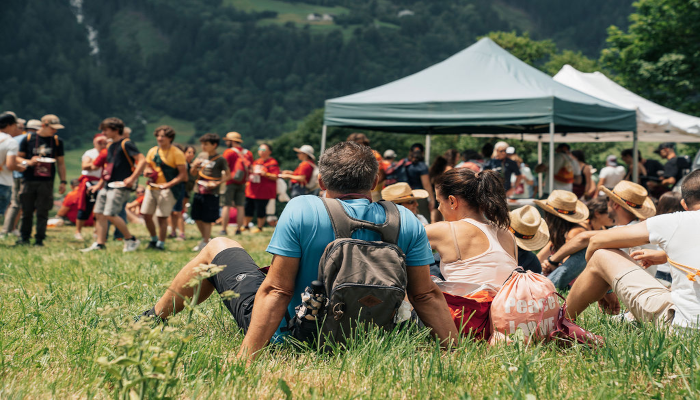 persone-sedute-in-un-prato-di-montagna-con-sacchi-in-spalla-pronti-a-partecipare-alla-famosa-stramangiada-di-poschiavo